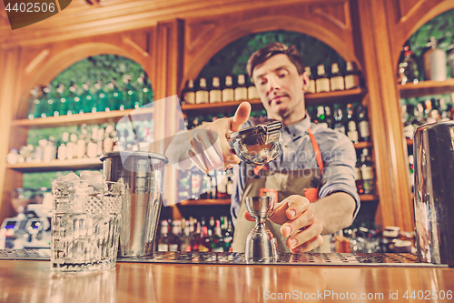 Image of Expert barman is making cocktail at night club.