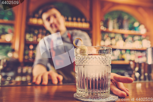 Image of Barman offering an alcoholic cocktail at the bar counter on the bar background