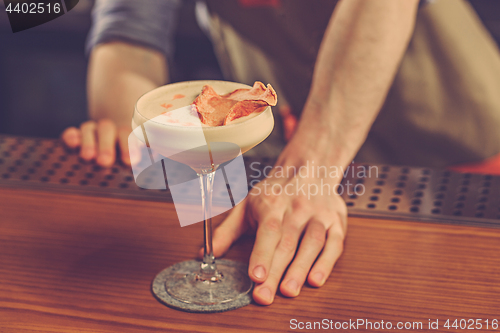 Image of Barman offering an alcoholic cocktail at the bar counter on the bar background