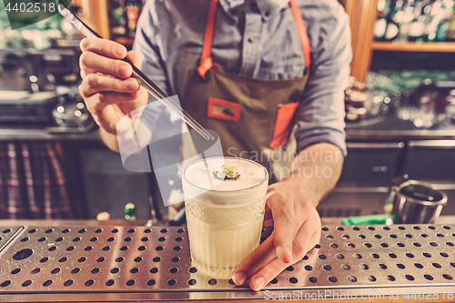 Image of Expert barman is making cocktail at night club.