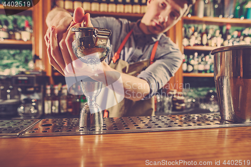 Image of Expert barman is making cocktail at night club.