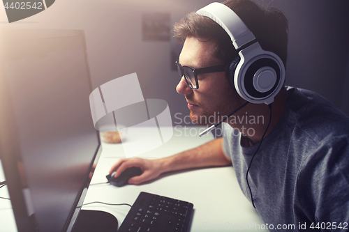 Image of man in headset playing computer video game at home