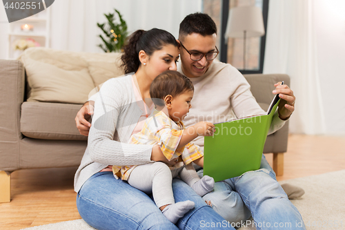Image of happy family with baby reading book at home