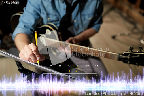 Image of musician with guitar and music book at studio