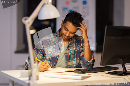 Image of creative man with notebook working at night office