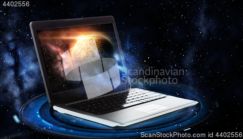 Image of laptop with virtual planet and space hologram