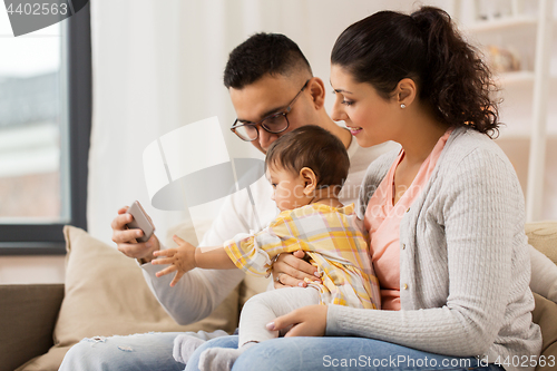 Image of mother, father and baby with smartphone at home