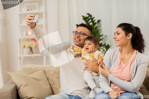 Image of mother and father with baby taking selfie at home