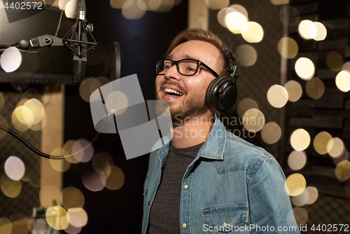 Image of man with headphones singing at recording studio