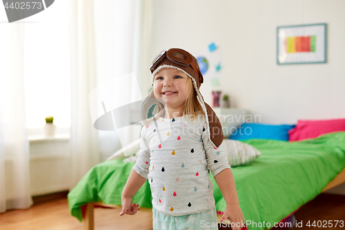 Image of happy little girl in pilot hat playing at home