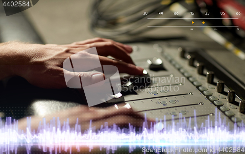 Image of hands on mixing console in music recording studio