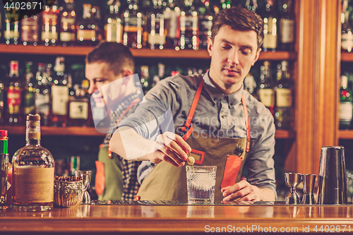 Image of Expert barman is making cocktail at night club.