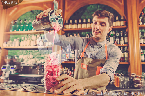 Image of Expert barman is making cocktail at night club.