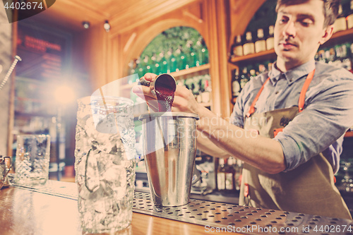 Image of Expert barman is making cocktail at night club.