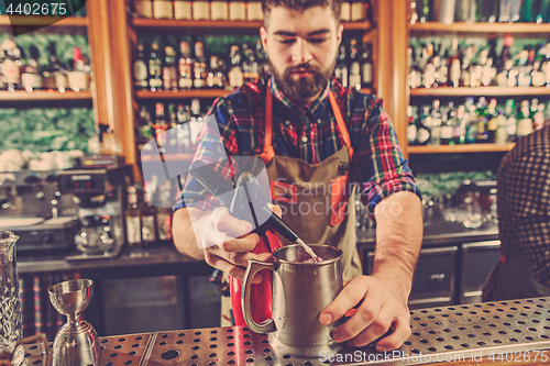 Image of Barman making an alcoholic cocktail at the bar counter on the bar background