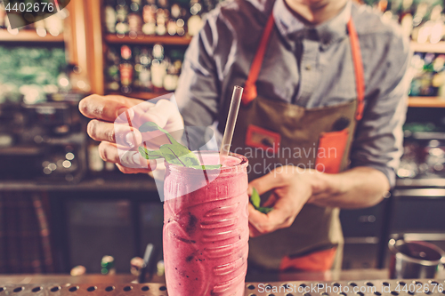 Image of Expert barman is making cocktail at night club.