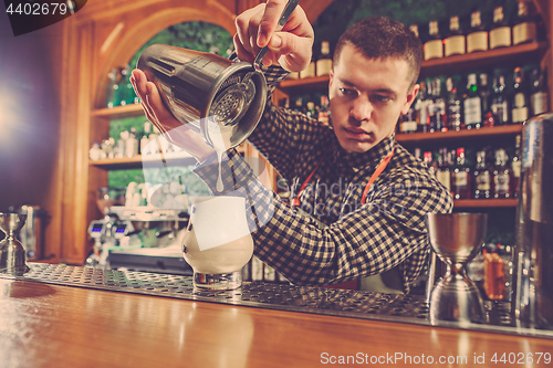 Image of Barman making an alcoholic cocktail at the bar counter on the bar background