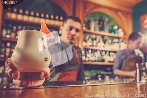 Image of Barman offering an alcoholic cocktail at the bar counter on the bar background
