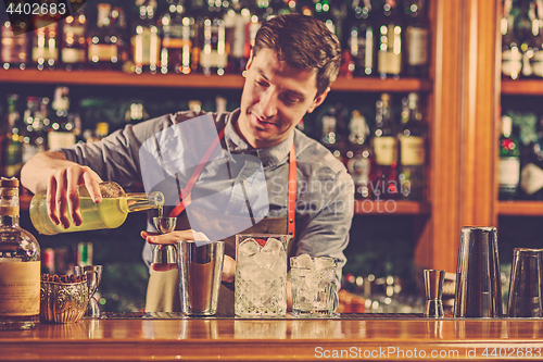 Image of Expert barman is making cocktail at night club.