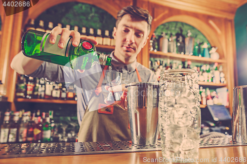 Image of Expert barman is making cocktail at night club.