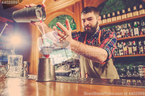 Image of Barman making an alcoholic cocktail at the bar counter on the bar background