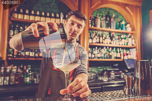 Image of Expert barman is making cocktail at night club.