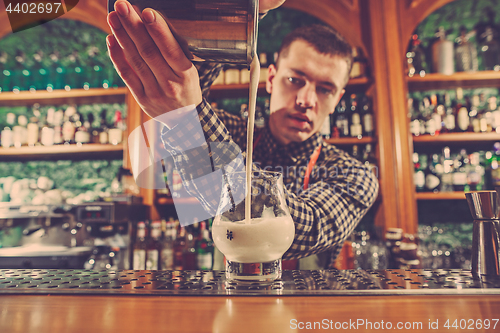 Image of Barman making an alcoholic cocktail at the bar counter on the bar background