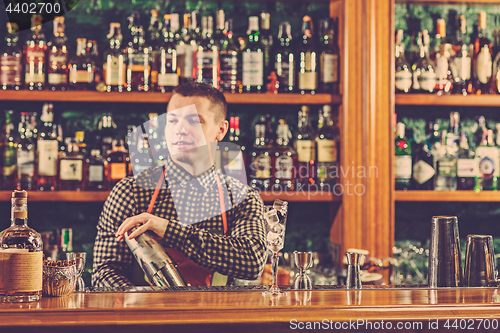 Image of Barman making an alcoholic cocktail at the bar counter on the bar background