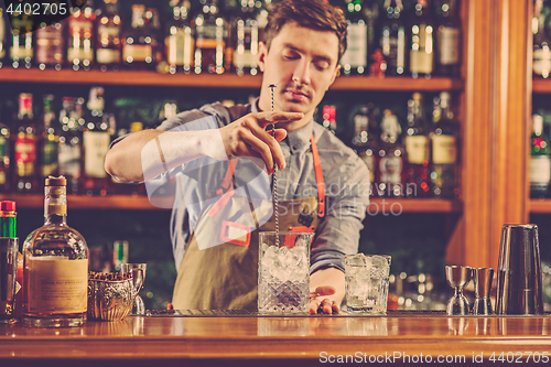 Image of Expert barman is making cocktail at night club.