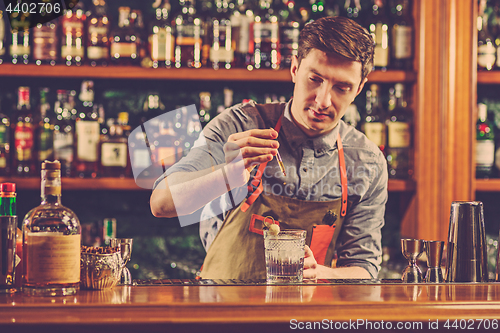 Image of Expert barman is making cocktail at night club.