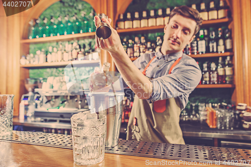 Image of Expert barman is making cocktail at night club.