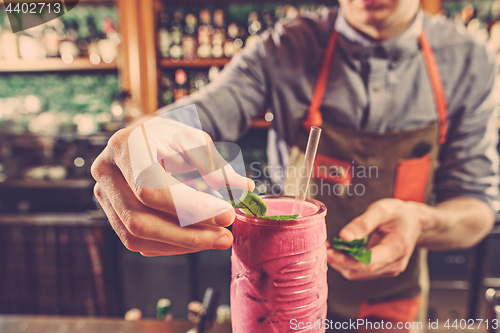 Image of Expert barman is making cocktail at night club.