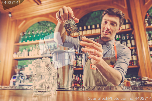 Image of Expert barman is making cocktail at night club.