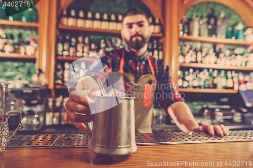 Image of Barman making an alcoholic cocktail at the bar counter on the bar background