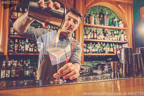 Image of Expert barman is making cocktail at night club.