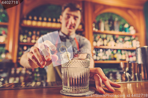 Image of Expert barman is making cocktail at night club.