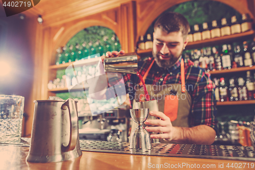 Image of Barman making an alcoholic cocktail at the bar counter on the bar background