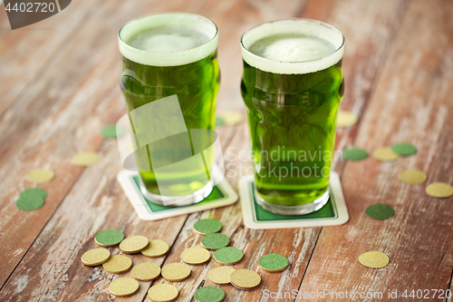 Image of glasses of green beer and gold coins on table