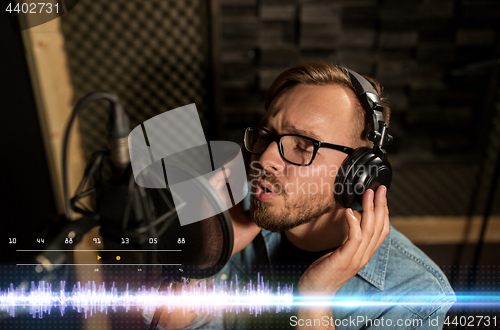 Image of man with headphones singing at recording studio