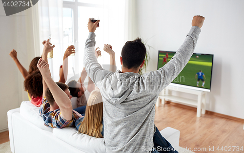 Image of friends watching soccer on tv and celebrating goal