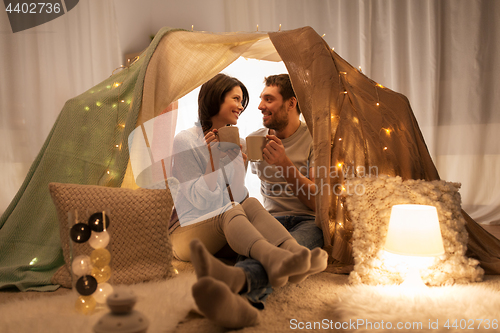 Image of couple drinking coffee or tea in kids tent at home