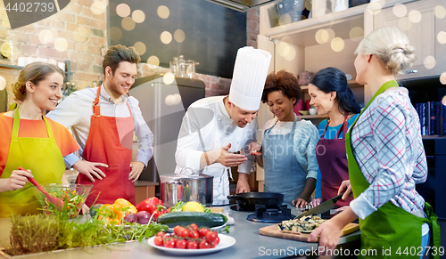 Image of happy friends and chef cook cooking in kitchen