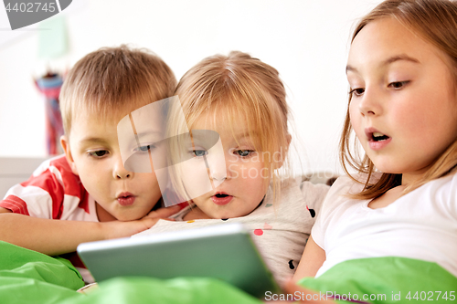 Image of little kids with tablet pc in bed at home