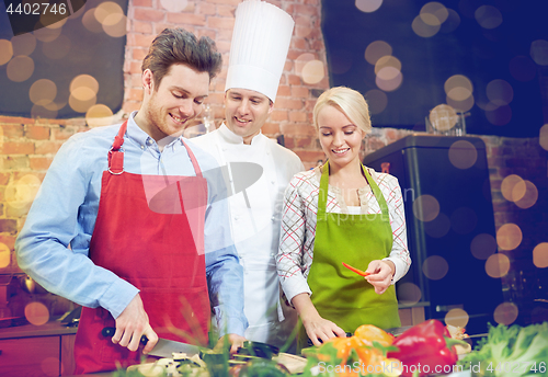 Image of happy couple and male chef cook cooking in kitchen