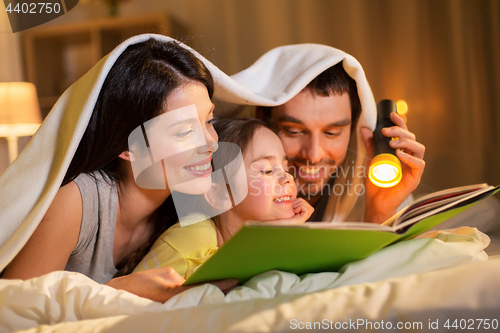 Image of happy family reading book in bed at night at home