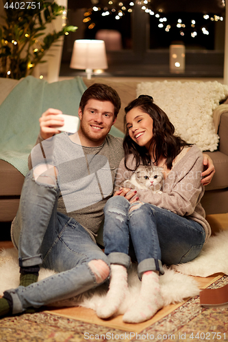 Image of happy couple taking selfie by smartphone at home