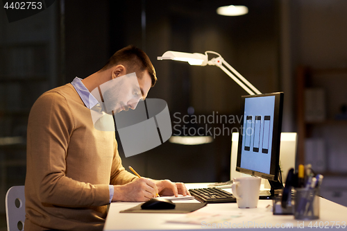 Image of man with notepad working at night office