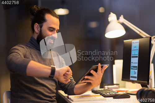 Image of man with smartwatch and tablet pc at night office