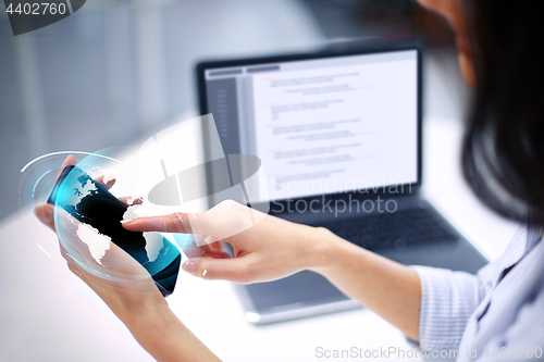 Image of businesswoman with smartphone and earth hologram