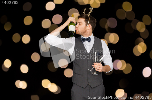 Image of man kissing bottle of champagne at christmas party